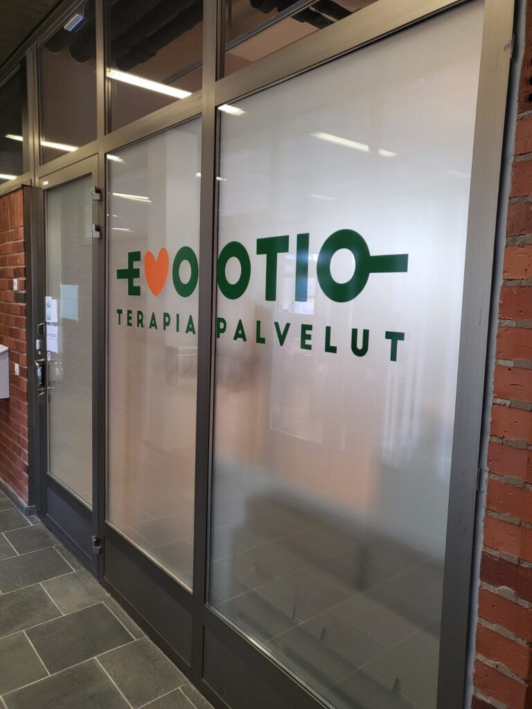 Liiketilan lasipinnat, joissa on näkösuojapinta ja yrityksen tunnus.